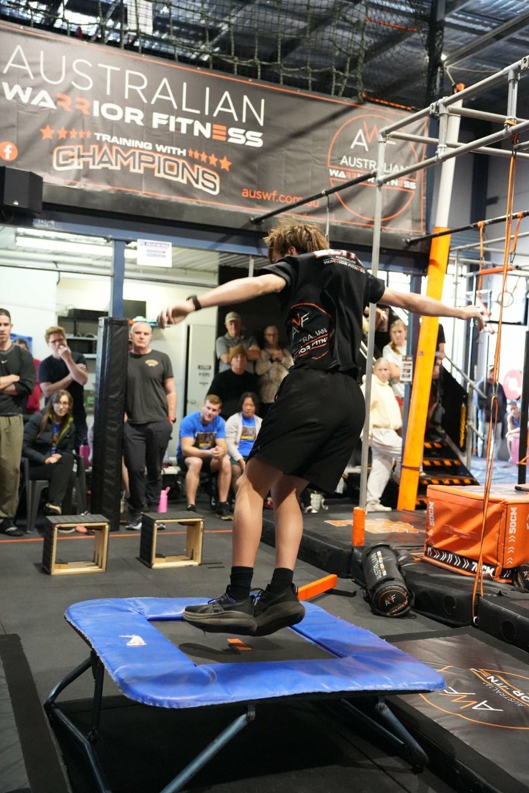 Young ninja bouncing off a mini trampoline under the Australian Warrior Fitness banner
