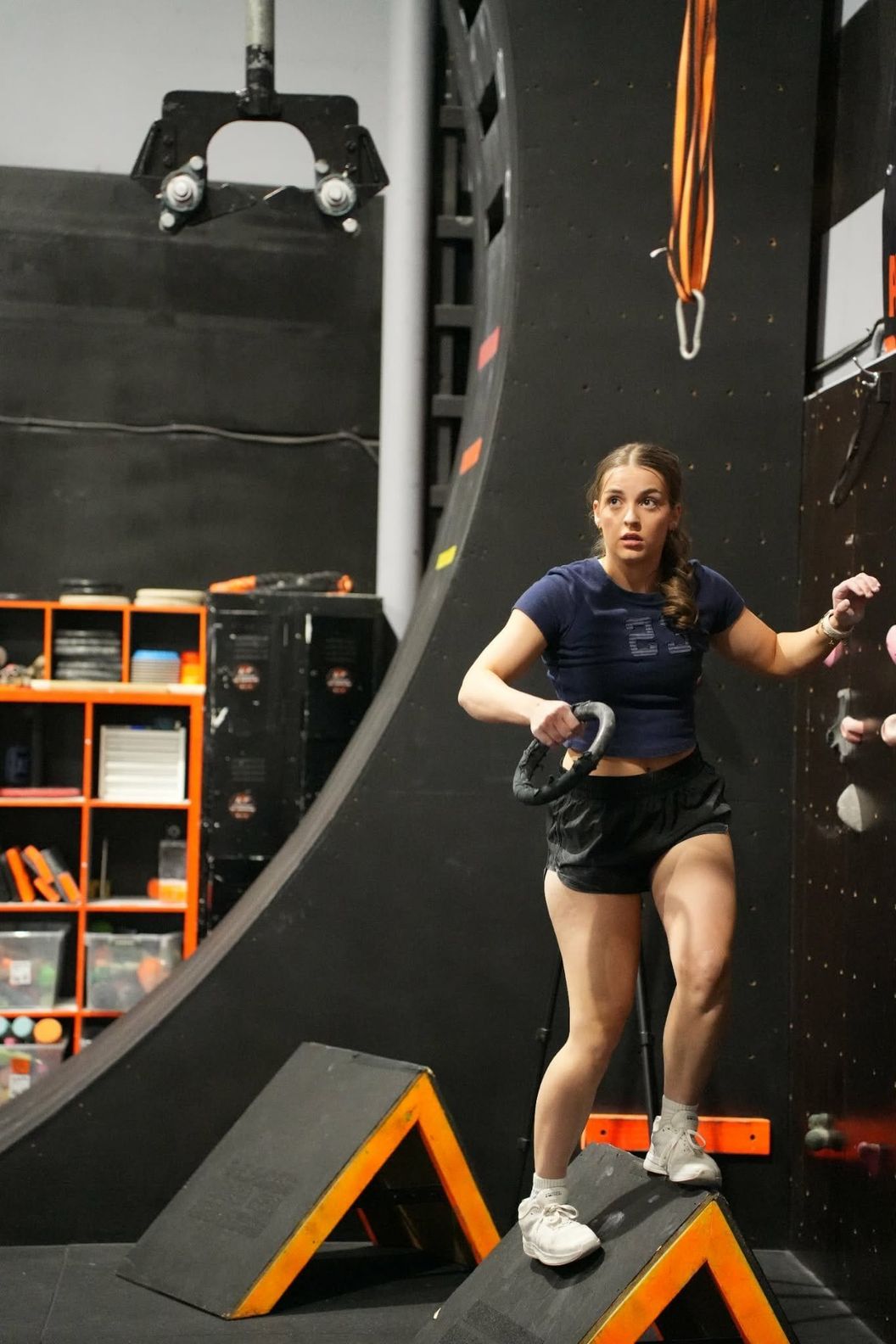 Young woman stepping across angled step obstacles near the AWF warped wall