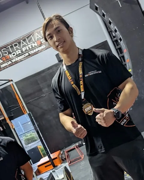 AWF coach Shen giving a thumbs up with his AWF medal