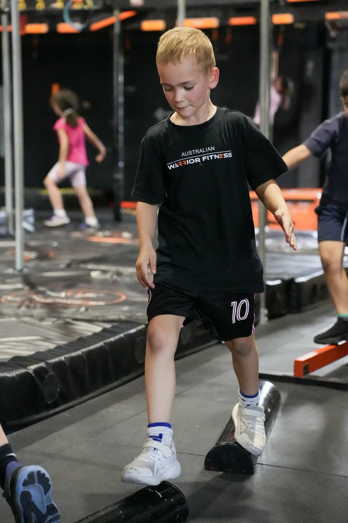 Boy crossing the balance beam at an AWF kids ninja party